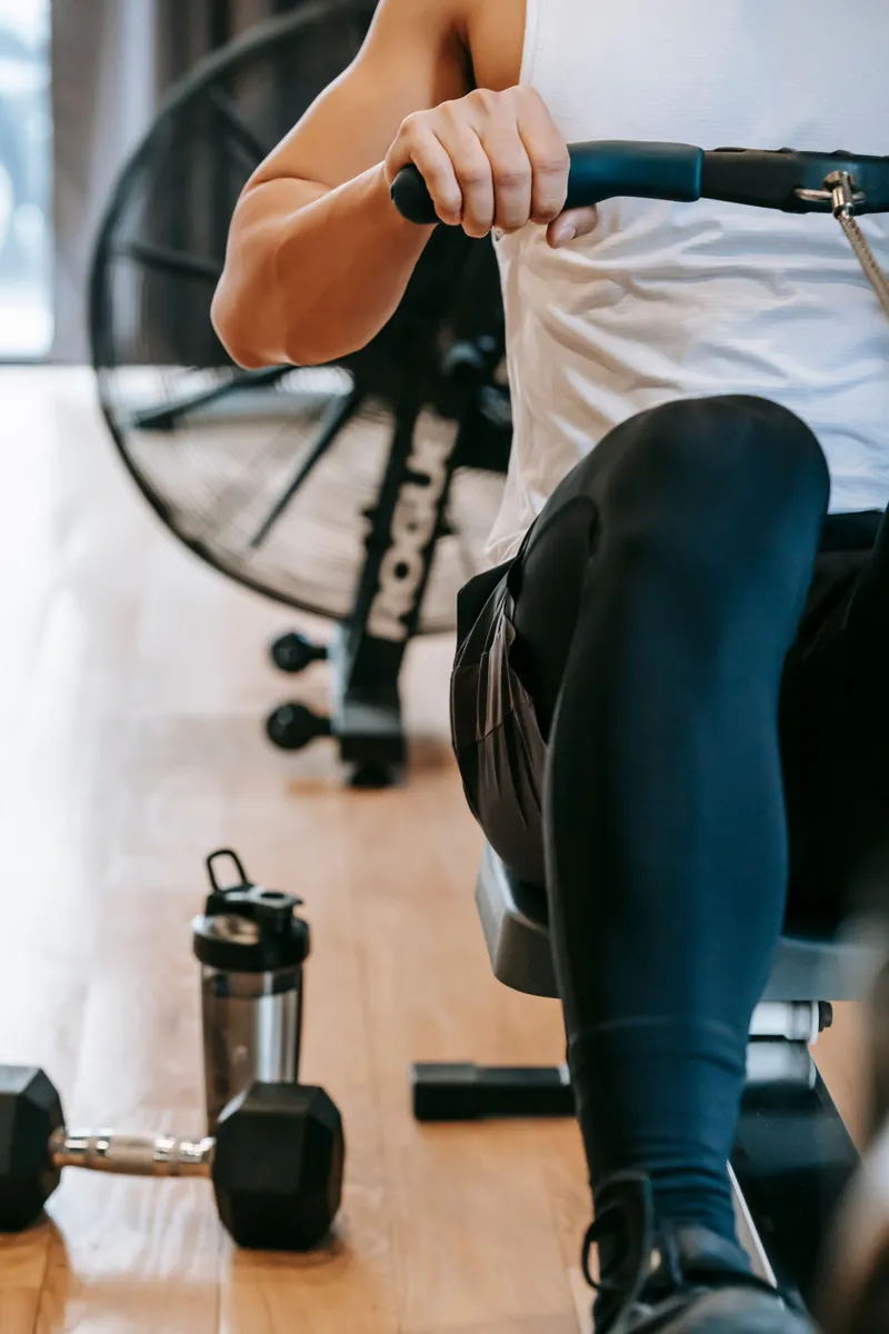 Person training on a rowing machine with a shaker bottle beside them