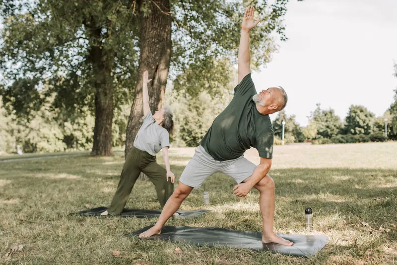 Older couple doing yoga in a park